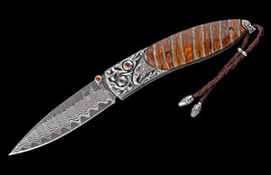 Folding knife with decorative handle and lanyard on a black background