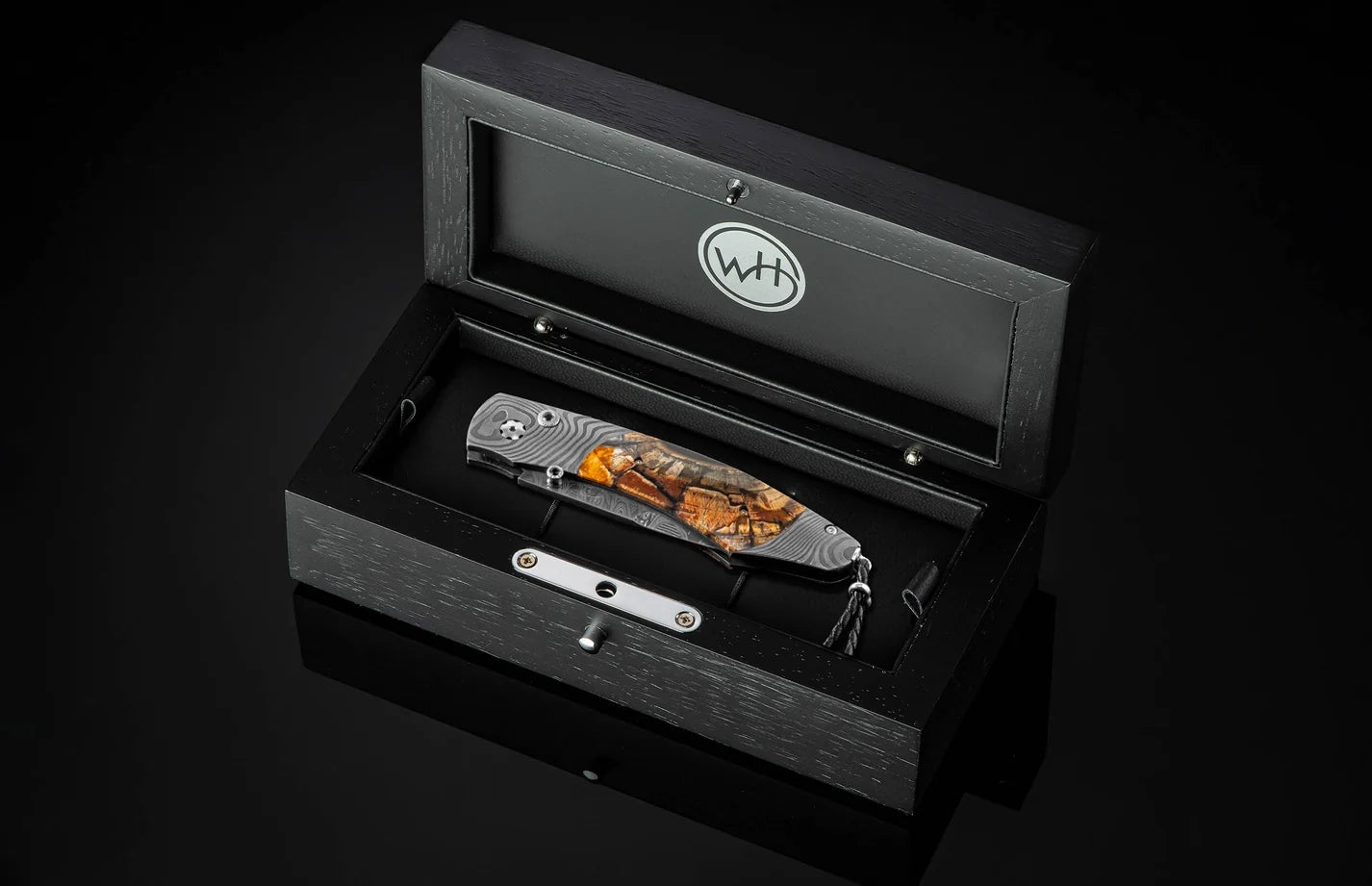 Black leather-bound knife set with a pocket knife and sheath in an open box on a black background.