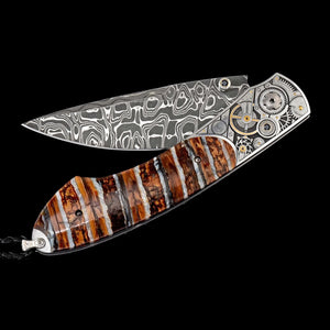 Open William Henry B12 Watch Gears III knife with Damascus blade, watch gear bolsters and mammoth tooth handle on black