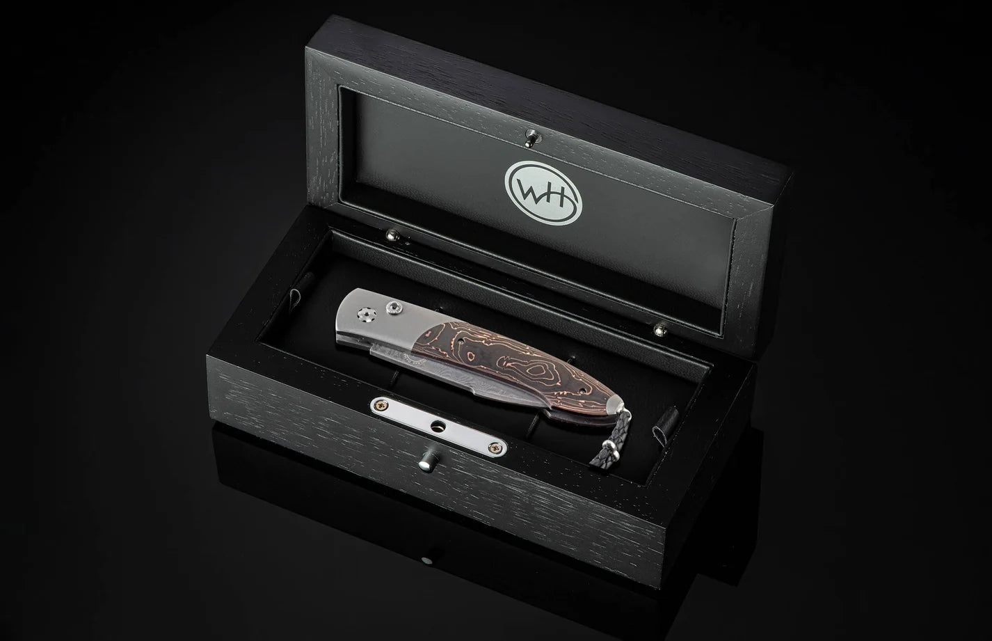 folding knife sitting in a dark wooden box 