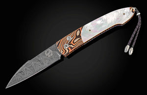 An open folding pocket knife with a patterned Damascus steel blade, a white mother-of-pearl inlay, and a handle featuring orange, brown, and black wood grain swirls, shown against a dark background.