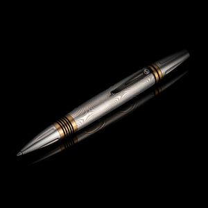 Diagonal view of William Henry Caribe 16 pen showing Damascus steel barrel and brass spacers on reflective black background