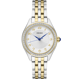 A Seiko women's two-tone stainless steel and gold-tone watch with a white sunburst dial, crystal-encrusted bezel, and blue hands, shown on a plain white background.