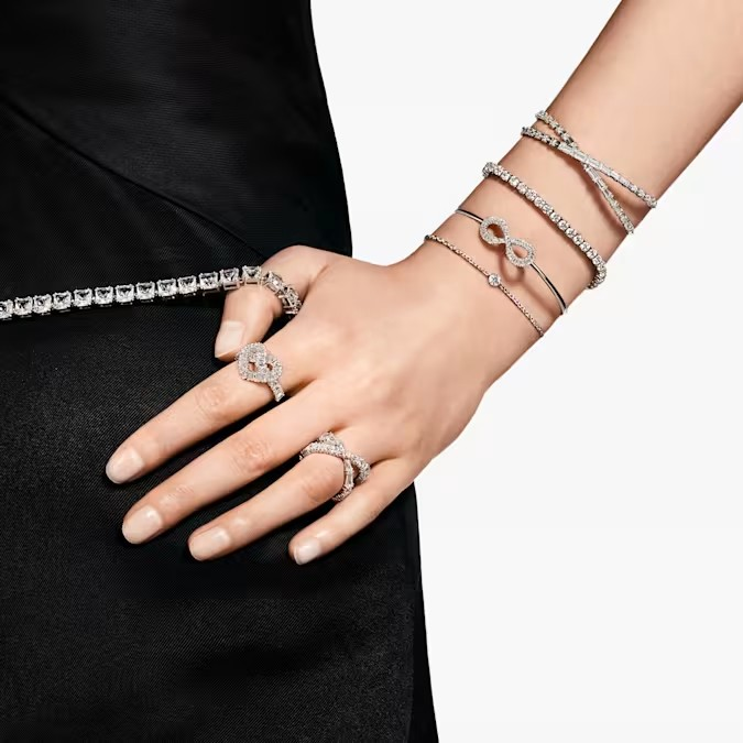 Three-quarter view of Hyperbola ring on model finger showcasing rhodium-plated infinity pave diamonds on black background