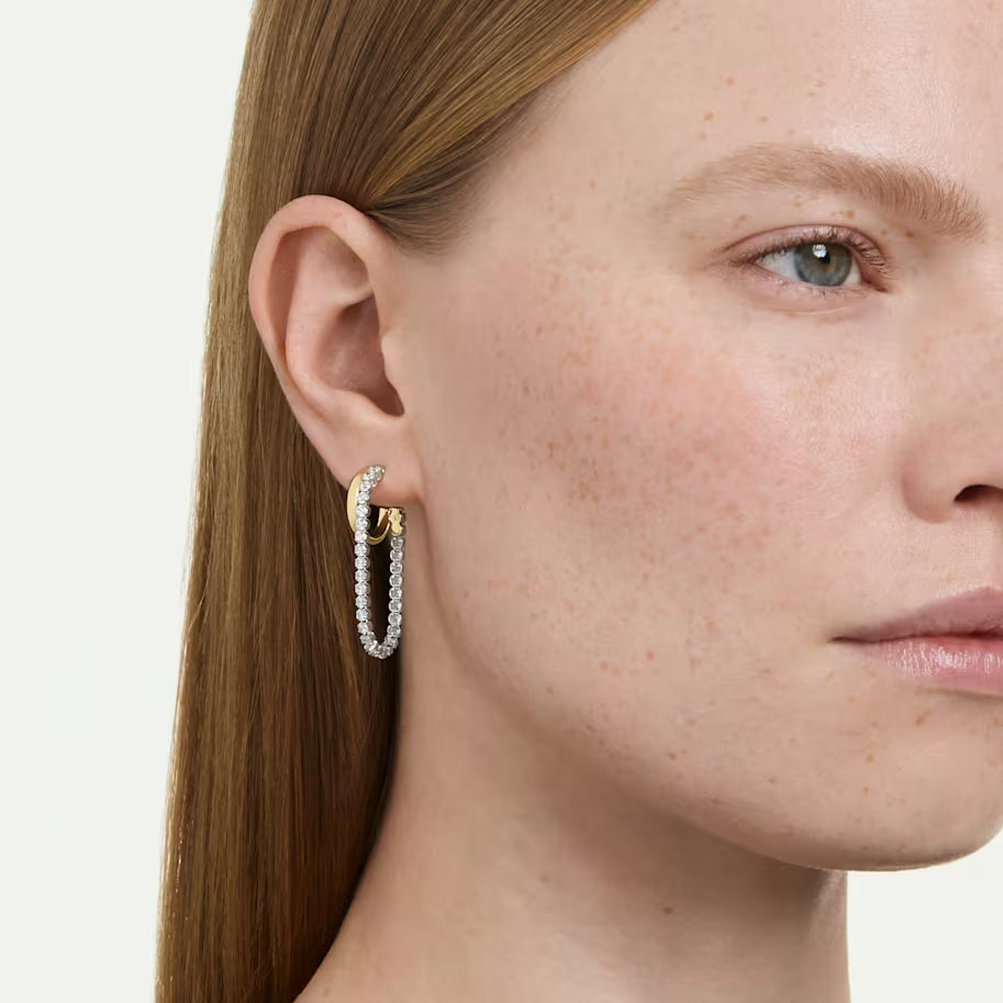 a model wearing round cut drop earrings with gold tone hoops on a white background