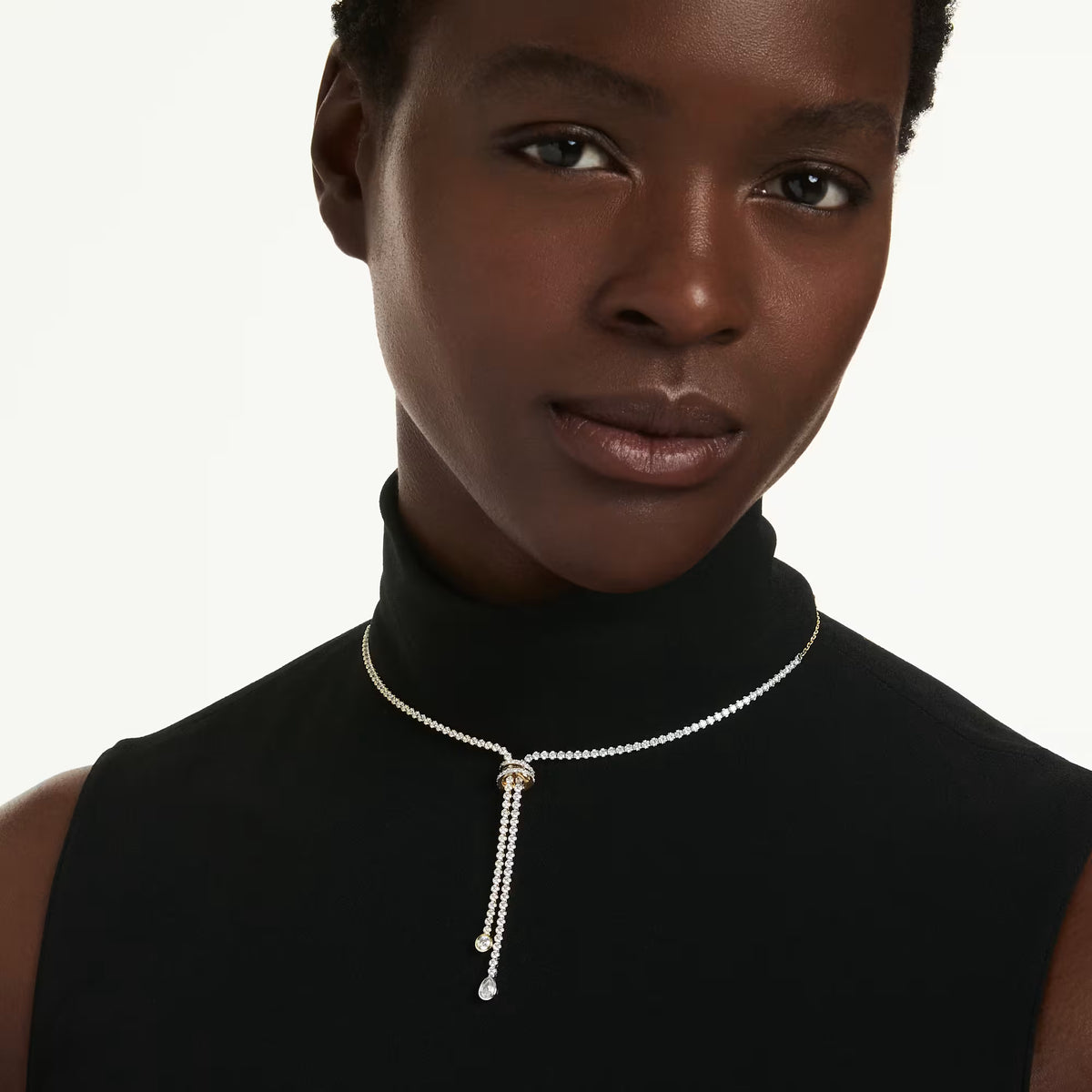 model wearing a black shirt and a mixed tone y neclace with crystals on a white necklace