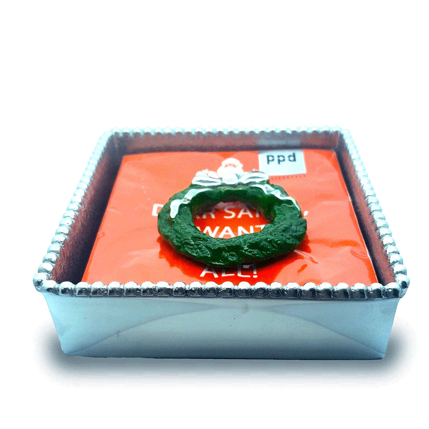 Silver beaded napkin box with green wreath on red napkin reading DEAR SANTA I WANT IT ALL! and ppd