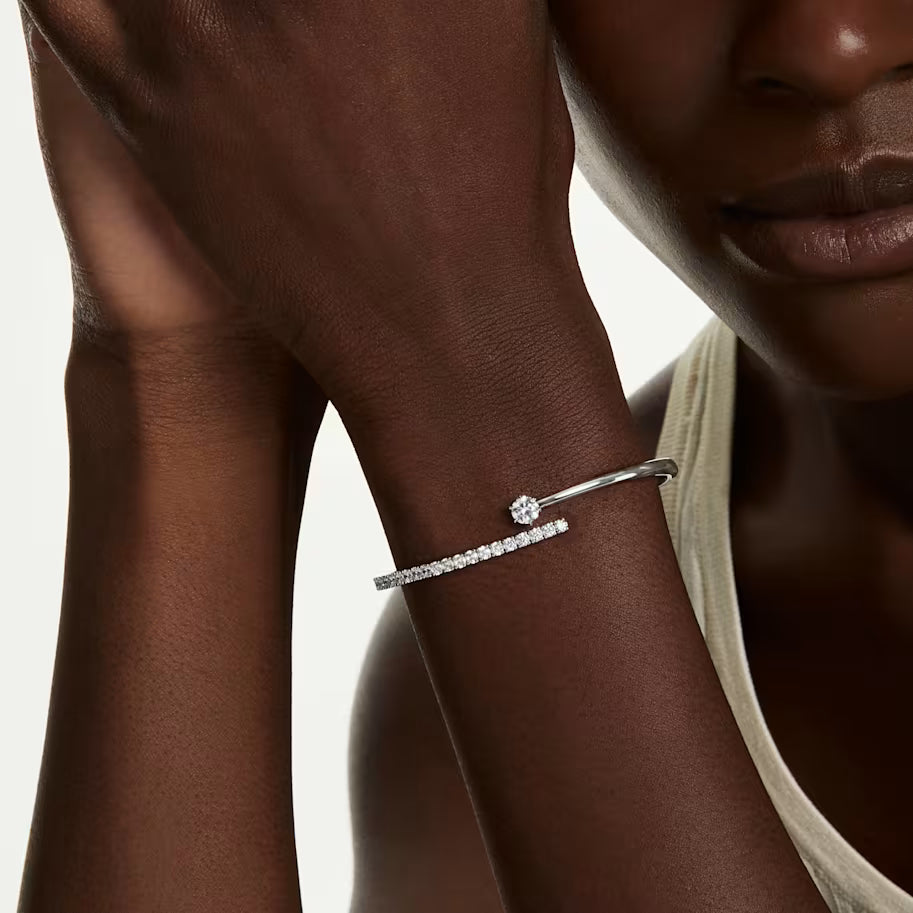 a model wearing Silver tone open bangle bracelet with zirconia stones on white background