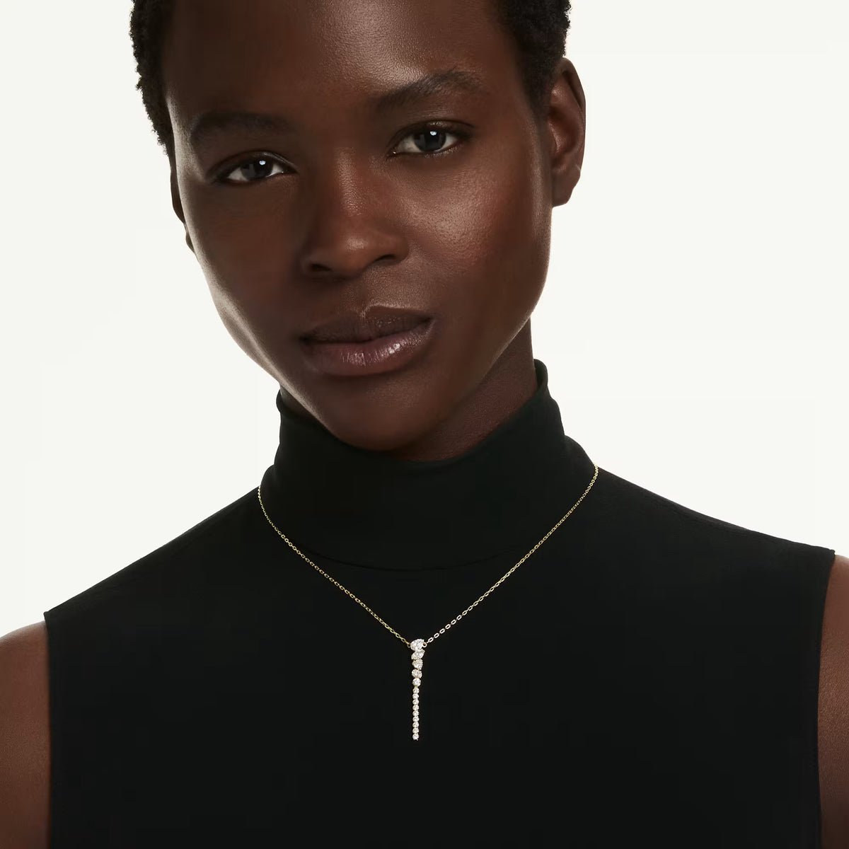 a model wearing a Gold tone Zirconia arranged in a gradient of sizes, this y-shape necklace on a white background