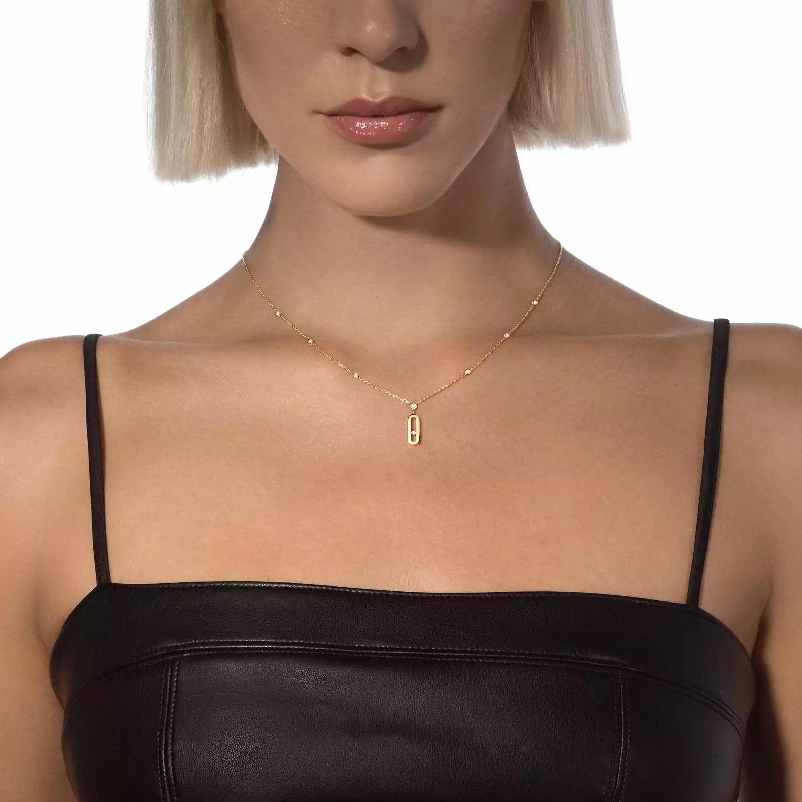 Woman wearing a gold necklace with a rectangular pendant on a white background