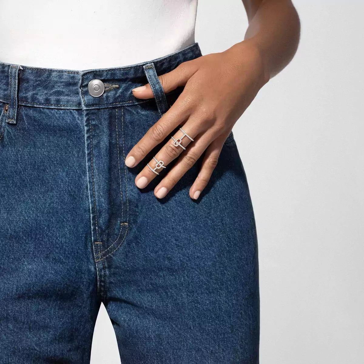 Person wearing blue jeans with a close-up of a hand adorned with 1ctw White Gold Double Pavé Diamond Ring