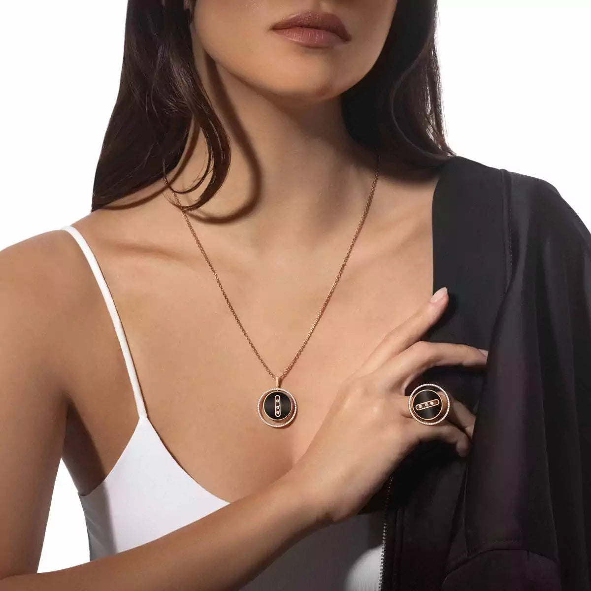 Woman wearing a gold necklace and ring with a black background