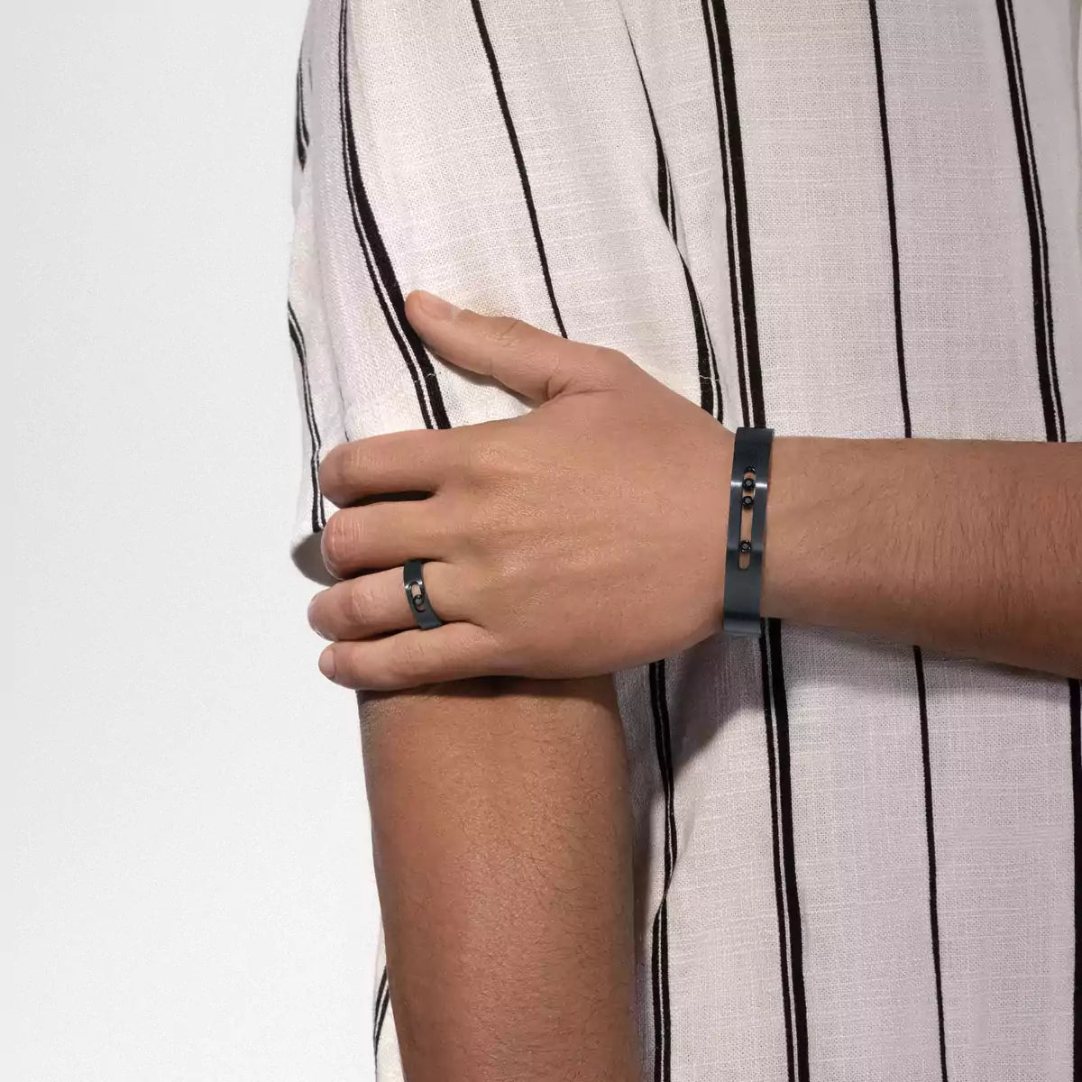 Person wearing a bracelet and ring with a white and black striped shirt