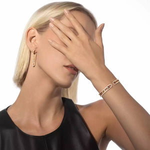 Woman with blonde hair and gold jewelry covering her face on a white background