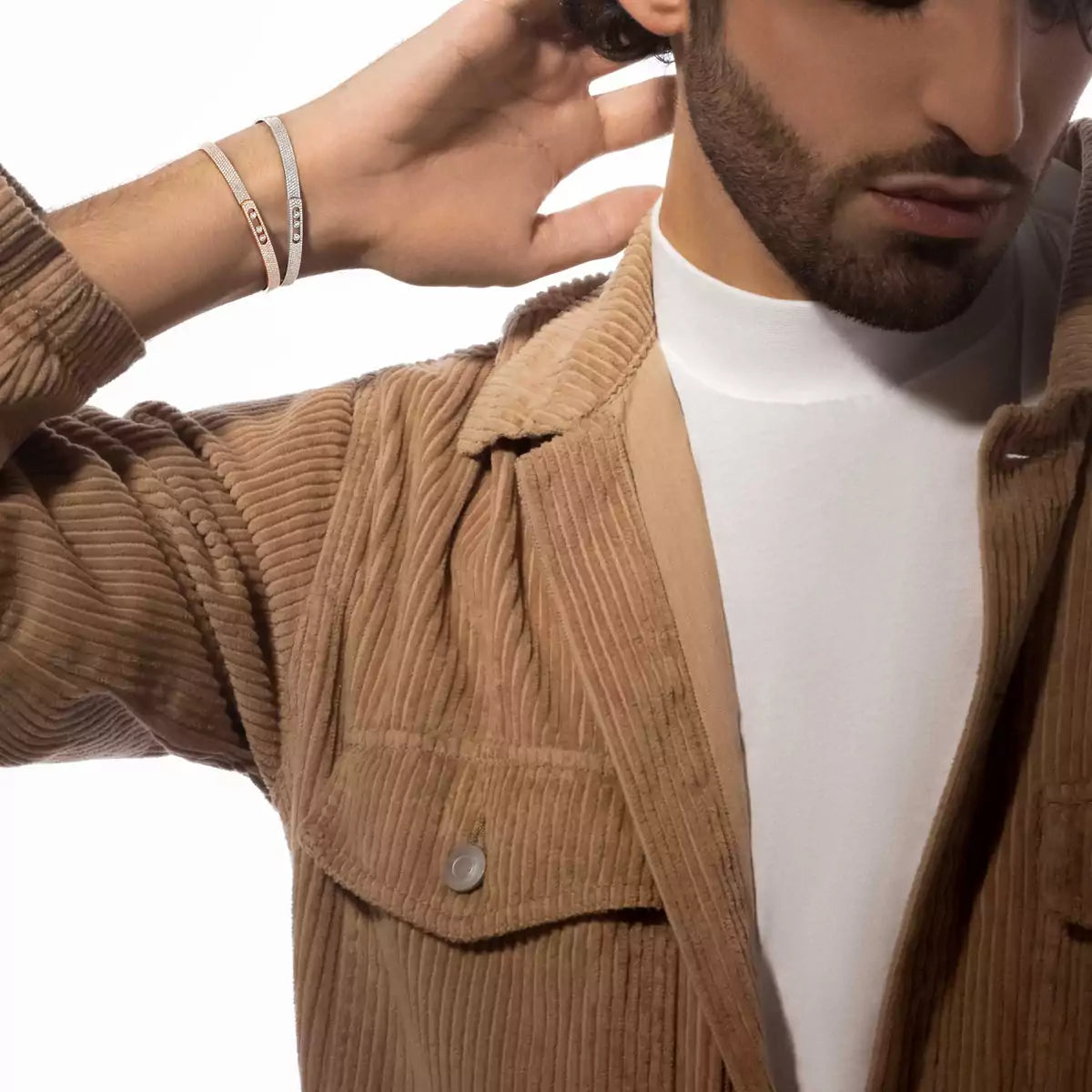 Man wearing a brown corduroy jacket over a white shirt on a white background