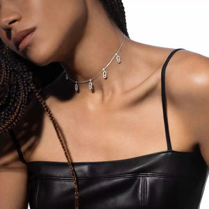 Woman wearing a black leather top and silver necklace on a neutral background