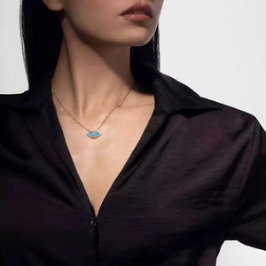 Person wearing a black shirt with a necklace featuring an eye pendant.