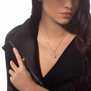 Woman wearing a gold necklace with a circular pendant on a white background