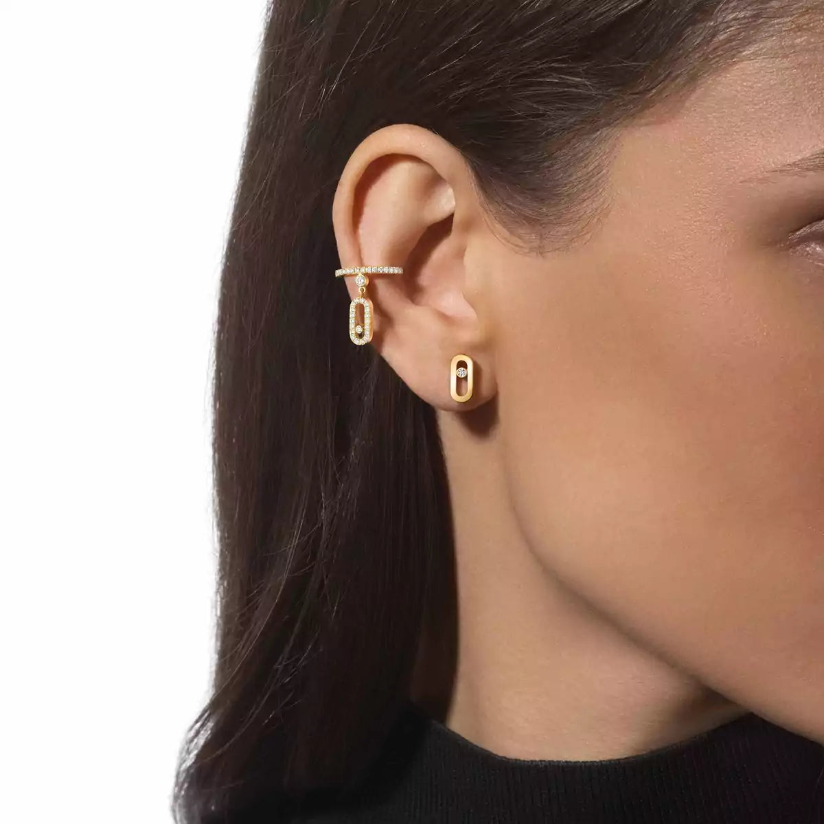 Close-up of a person wearing gold hoop earrings with a plain background