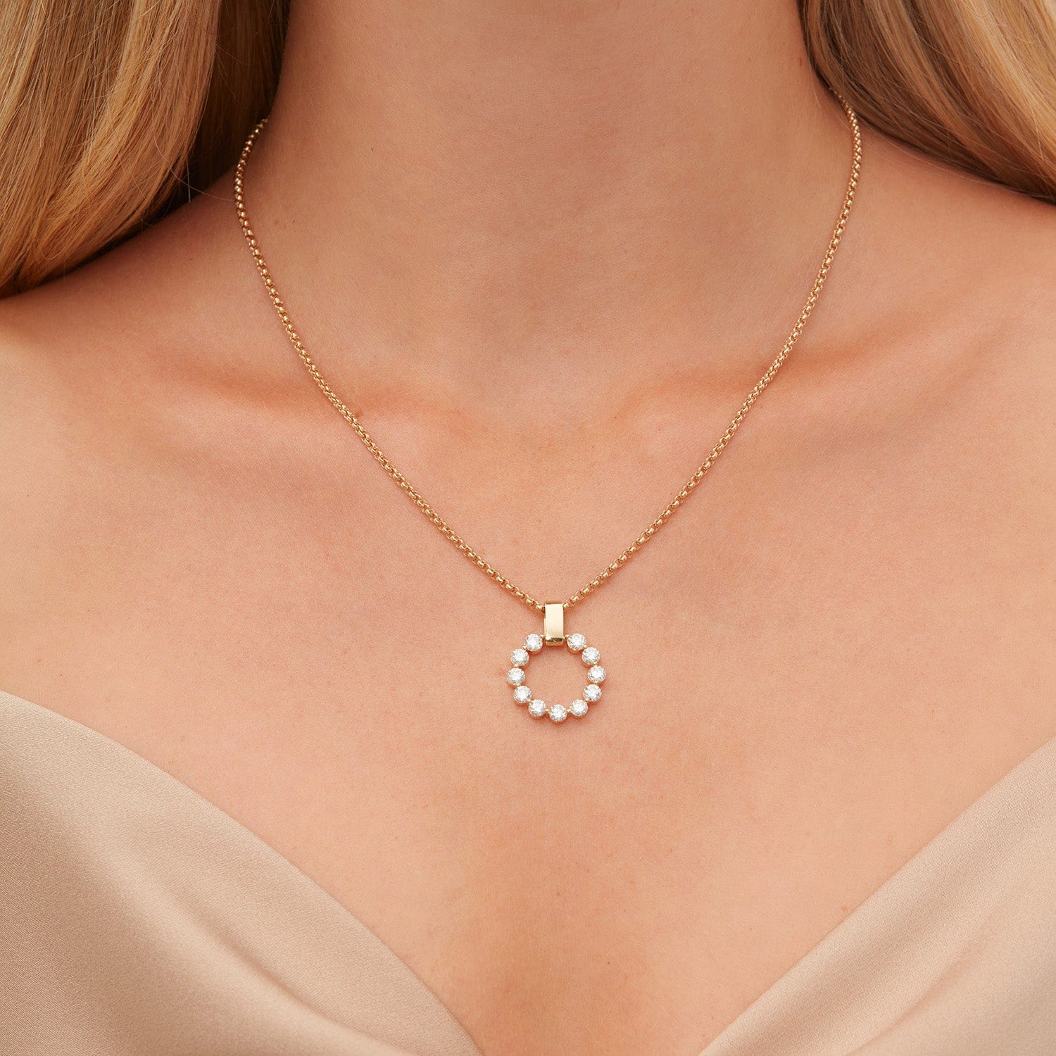 Front view of Large Cloud pendant necklace in yellow gold showcasing circular diamond cluster and square bail on a delicate chain against model's bare décolletage