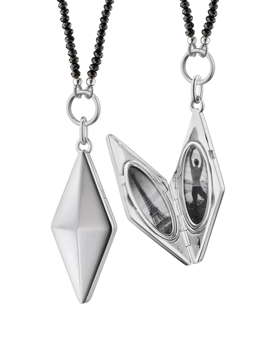 a silver diamond shaped locket that holds two images and has a black chain on a white background
