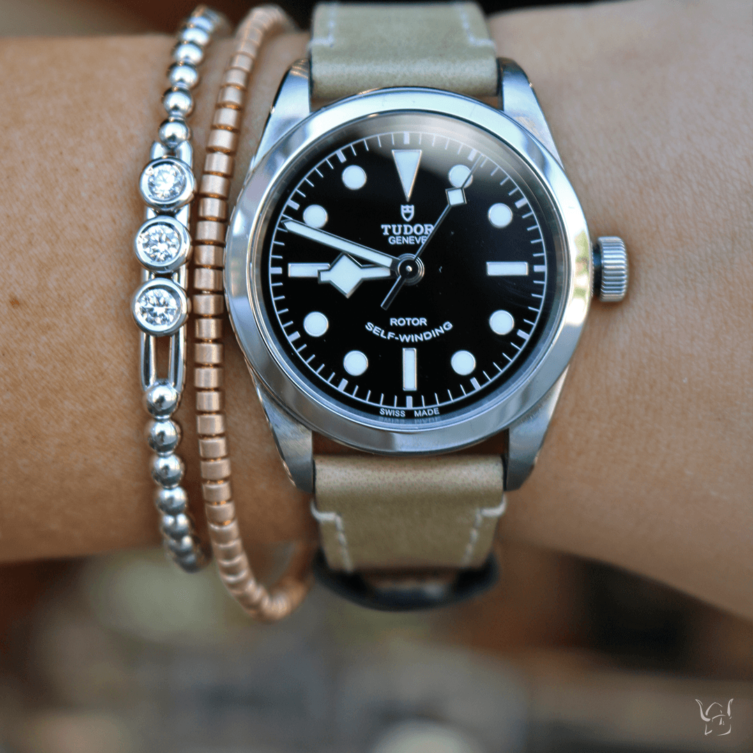 Tudor watch with black dial: TUDOR GENEVE ROTOR SELF-WINDING SWISS MADE; pink-gold and diamond stretch bracelets on wrist