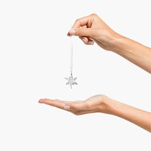 hands holding a crystal star ornament with white ribbon on a white background