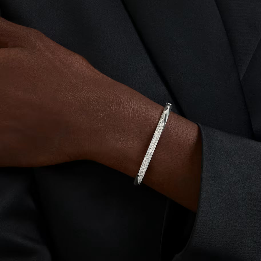 up close of a woman wearing a silver and crystal curved bangle bracelet on a white background