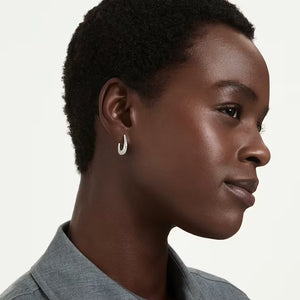a woman wearing silver and crystals oval hoop earings on a white background wearing a grey shirt