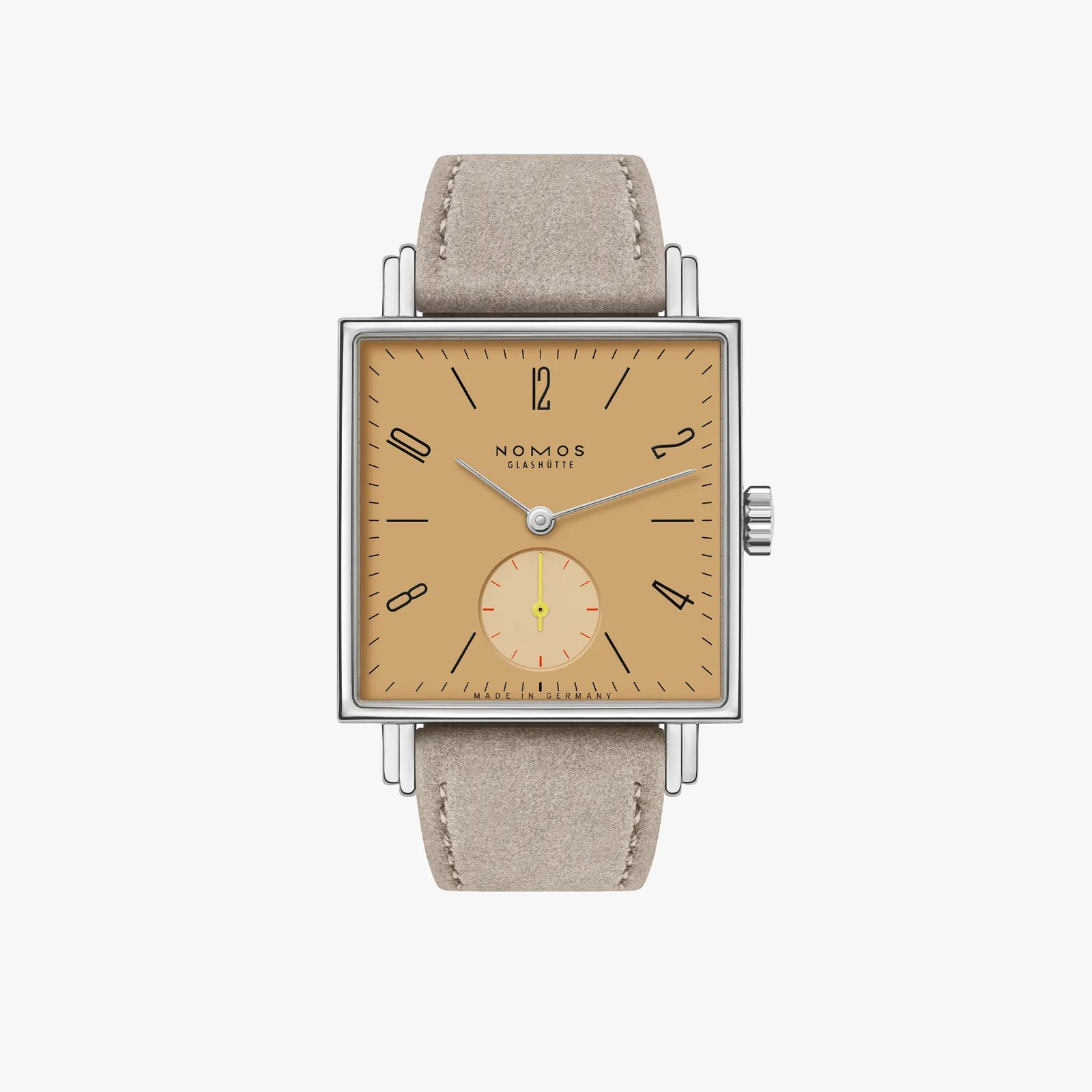 A NOMOS Calibre watch featuring a square silver-toned case, a warm tan dial with black Arabic numerals and a small subsidiary dial, and a light beige leather strap, shown against a plain light gray background.