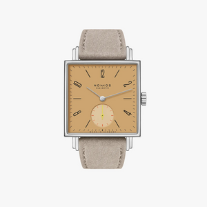 A NOMOS Calibre watch featuring a square silver-toned case, a warm tan dial with black Arabic numerals and a small subsidiary dial, and a light beige leather strap, shown against a plain light gray background.