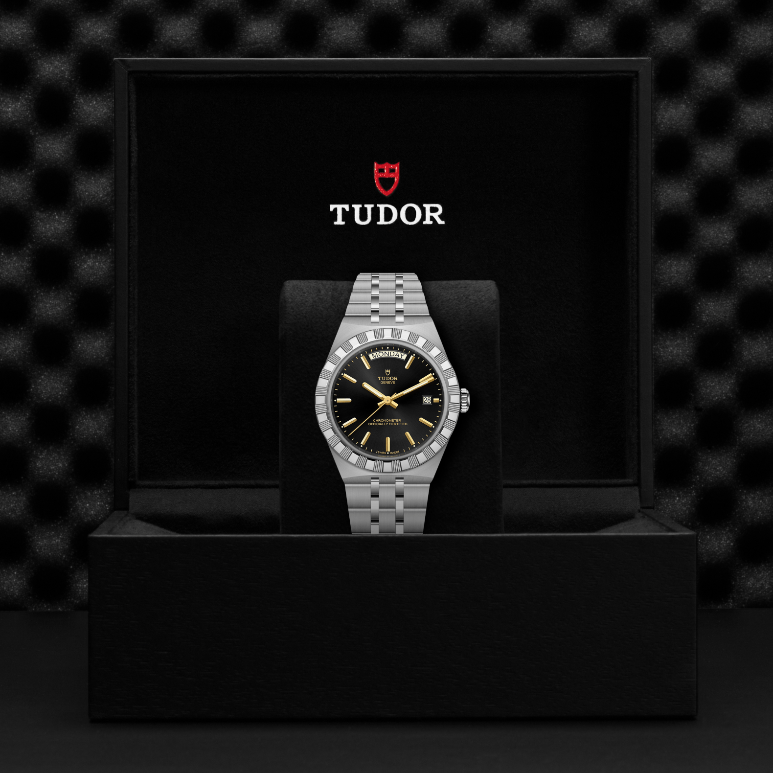 Tudor watch in a black box with the Tudor logo on a dark textured background