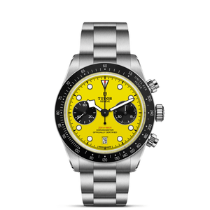 TUDOR watch with yellow dial with white and black markings with a steel bracelet on a white black background.