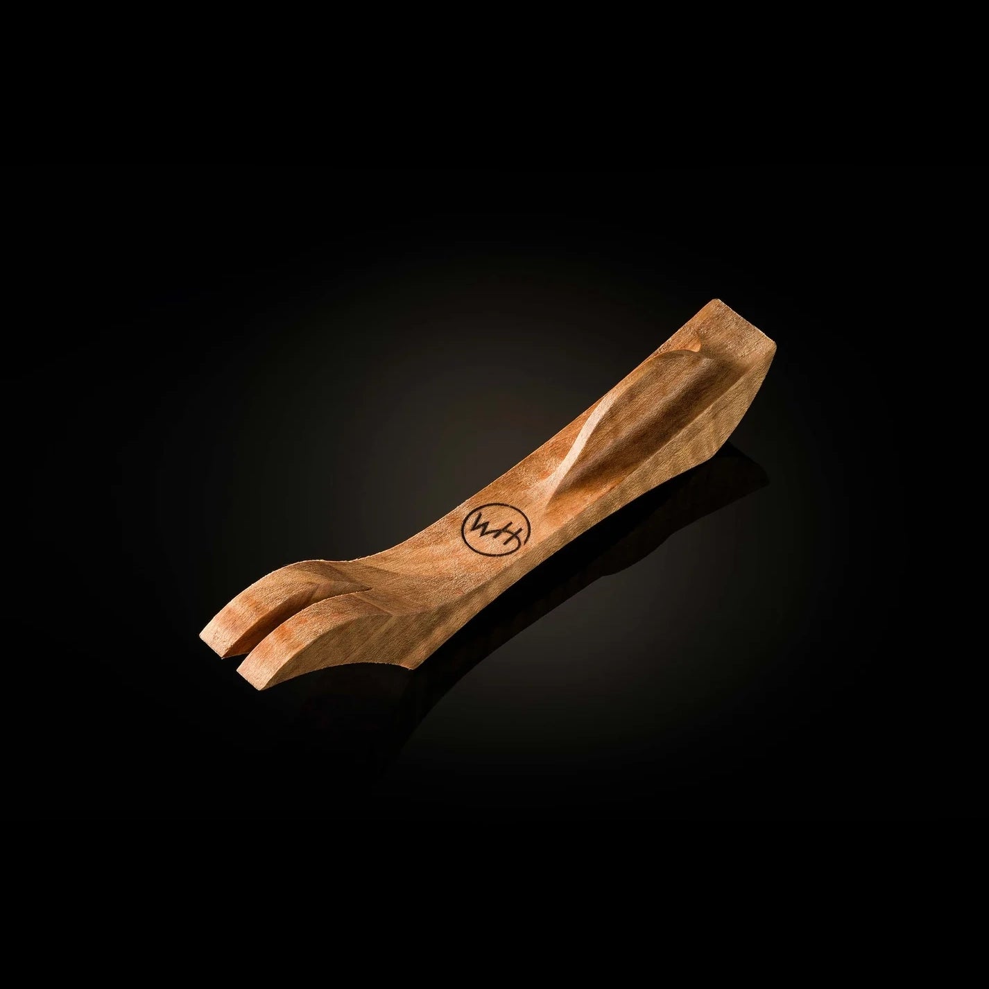 A carved wooden pocket knife holder with a polished finish and a circular 'W.H' logo engraved on the side, set against a dark reflective background.