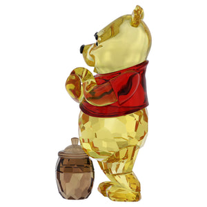 side view of winnie the pooh crystal figurine with a pot of honey by his feet on a white background