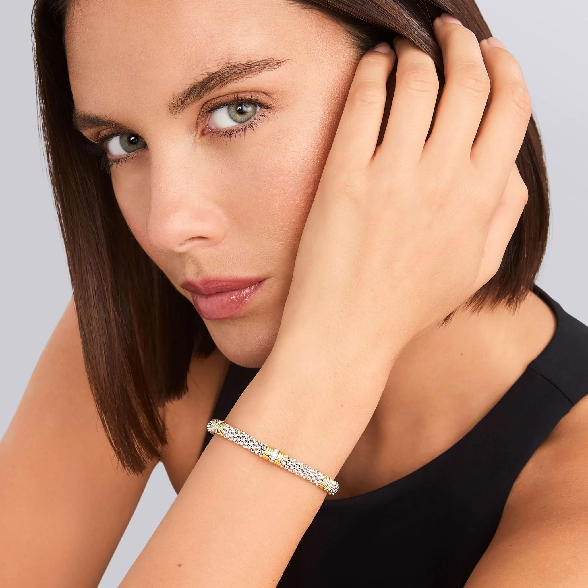 Close-up of wrist wearing Triple Diamond Caviar Bracelet 6mm showcasing three diamond stations and 18K gold accents on gray