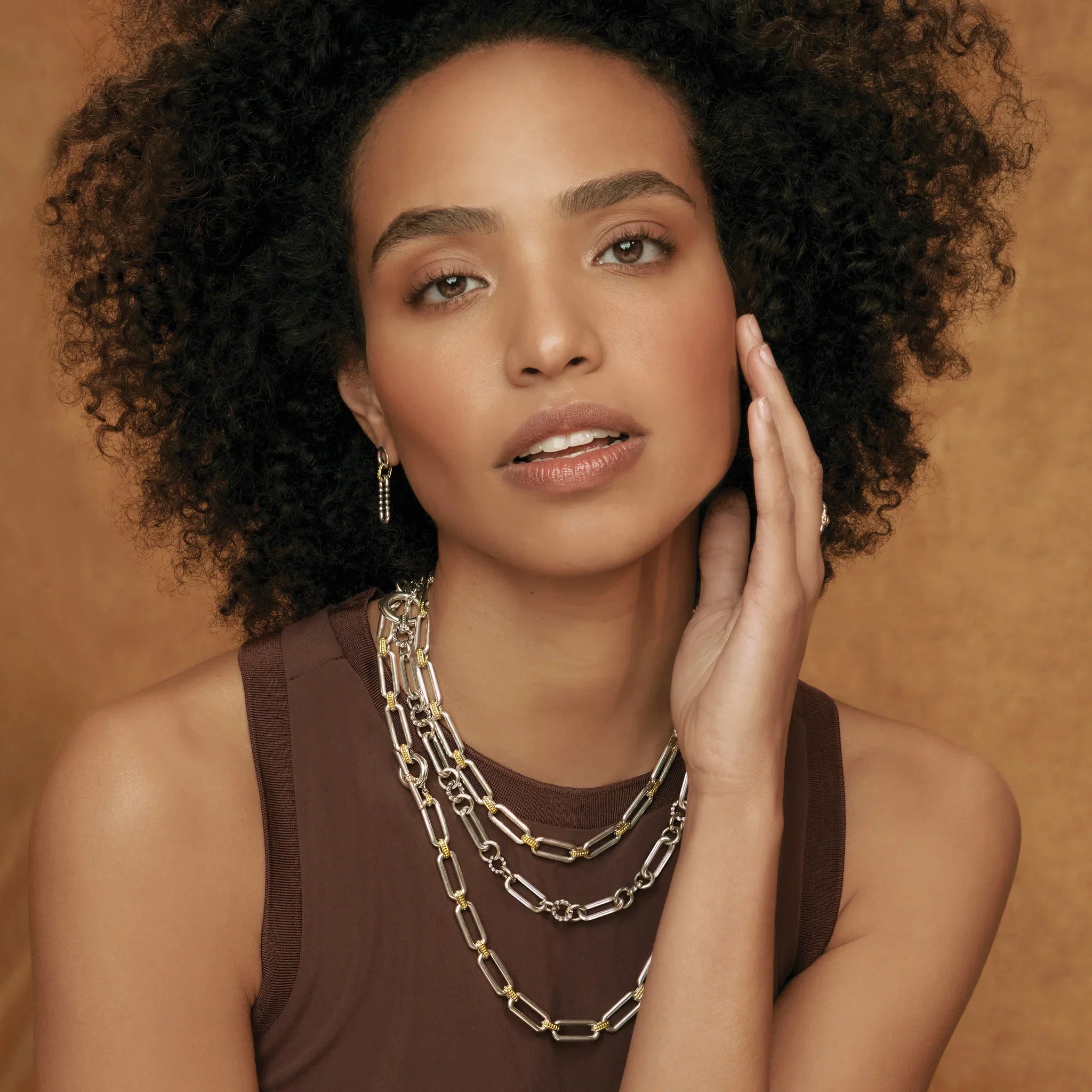 Front view of Two-Tone Link Necklace layered three times on model showing silver and 18k gold links on tan background
