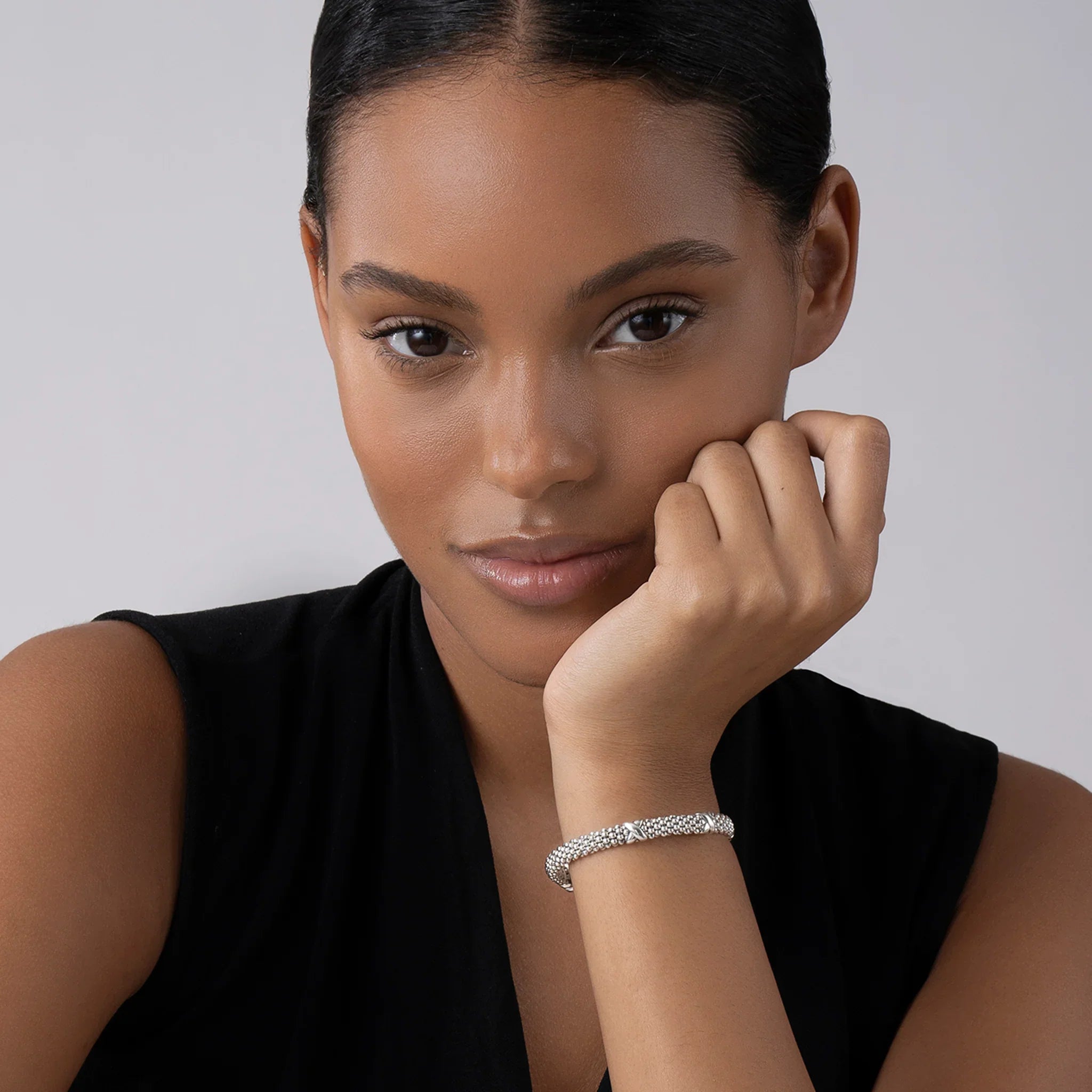 Close-up of wrist wearing 6mm Three Station X Caviar bracelet showing silver caviar beading and three sterling X stations on light gray
