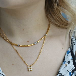Close-up of model's neckline wearing Pointelle gold cluster necklace with three-diamond pendant layered with a gold chain