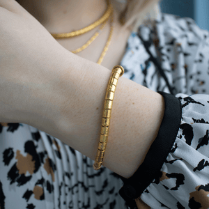 Close-up of Hammered Gold and Diamond Pendant Bracelet on wrist, showing 24K hammered gold texture against patterned blouse