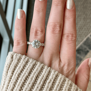 Top view of 1.18ctw diamond engagement ring showcasing large round center stone and diamond-set band on a hand with beige knit sleeve