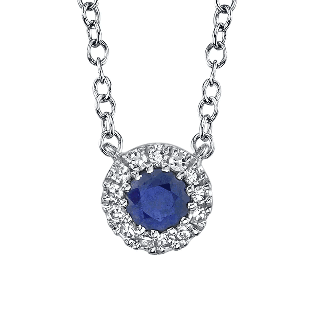 Round blue sapphire pendant with halo of small white diamonds on a delicate silver chain