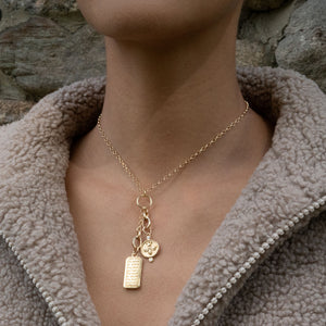 Front view of 18-inch yellow gold charm chain necklace with engraved tag and bee charm with pearl on tan fleece