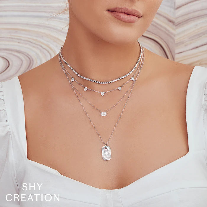 Front view of 14K white gold 0.95ctw diamond tennis choker layered with pendant necklaces on model wearing white top