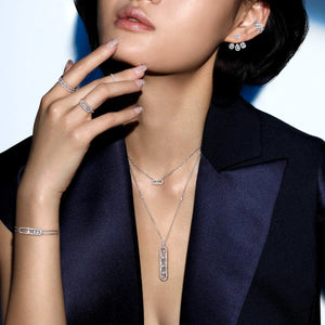 Woman wearing a black blazer and diamond rings, bracelet, earrings and necklaces on a white background