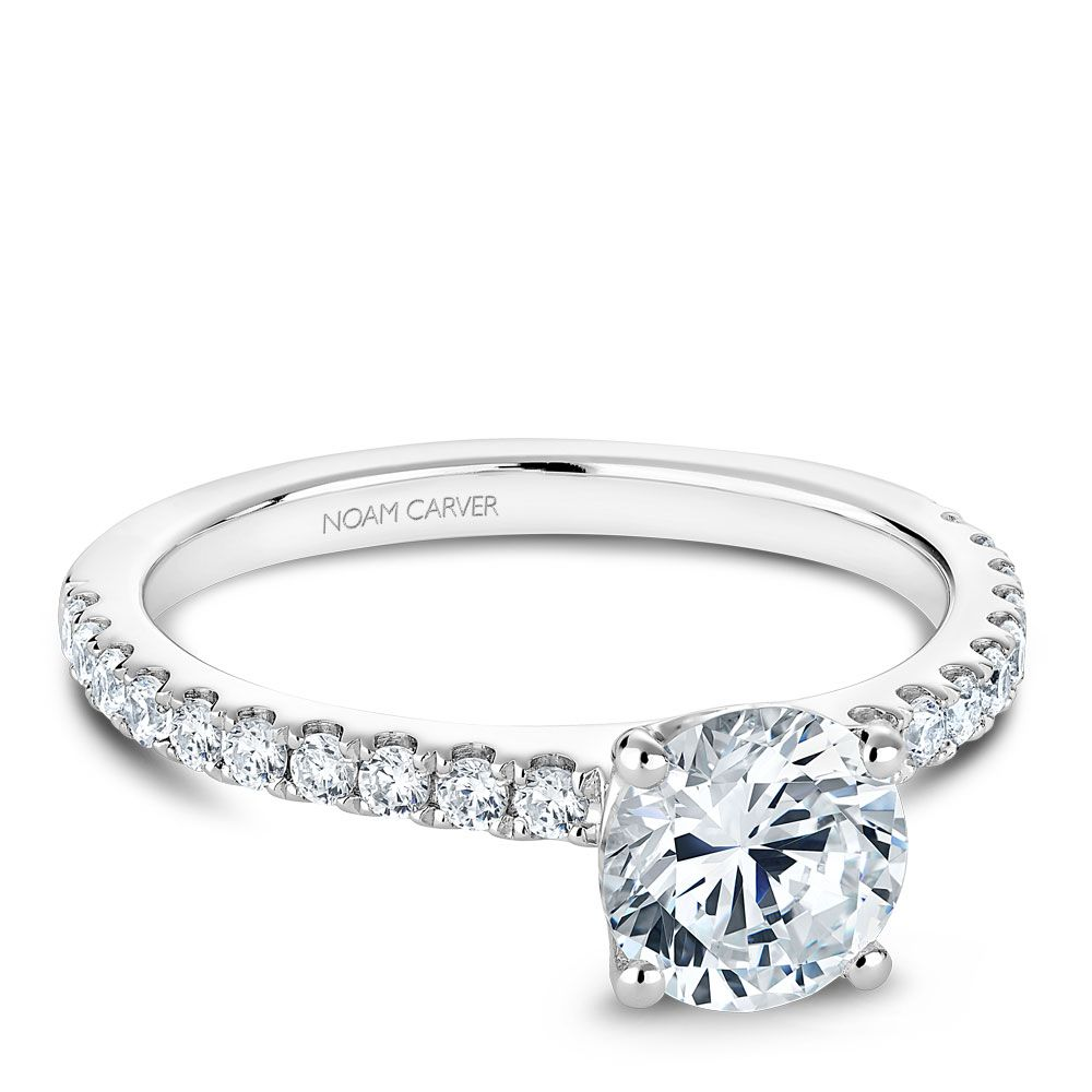 Noam Carver polished white metal solitaire engagement ring with round brilliant center stone and pavé diamond band