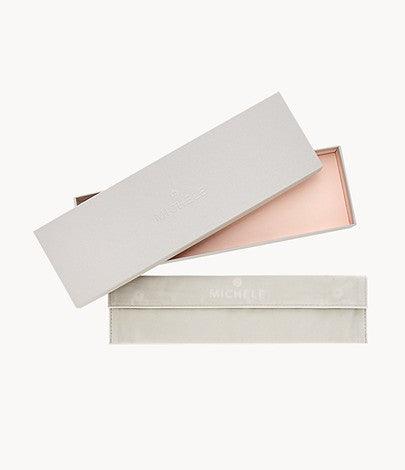 Top-down view of Michele gift box and suede pouch for two-tone pink gold-plated Apple Watch bracelet on white background